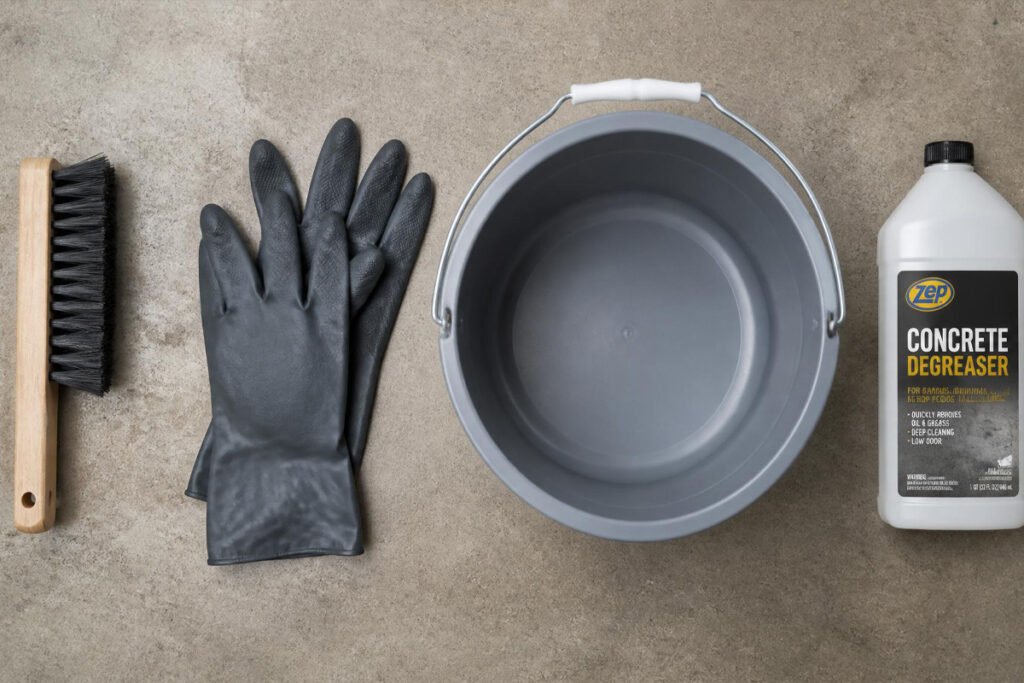 garage floor degreaser tools including scrub brush, bucket, and gloves