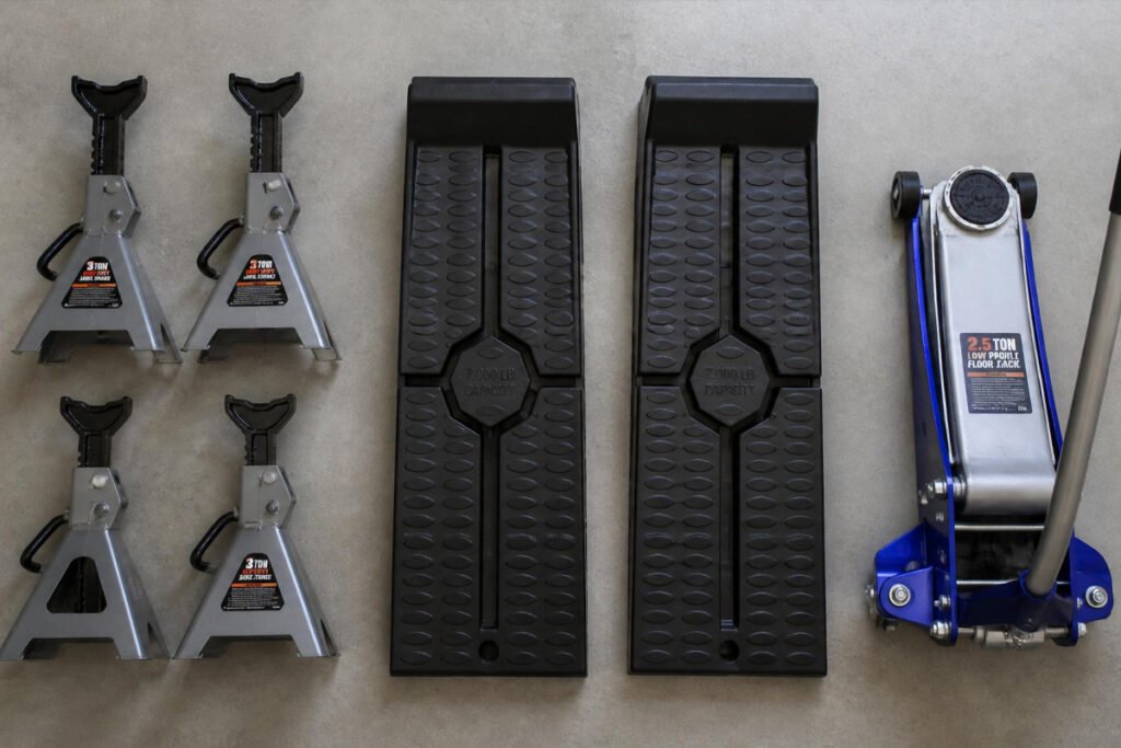 jack stands ramps and floor jack arranged on garage floor